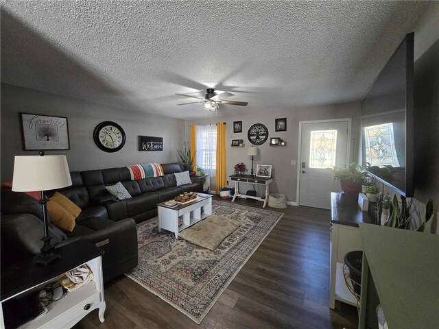 living room featuring a textured ceiling, dark wood-type flooring, and a healthy amount of sunlight