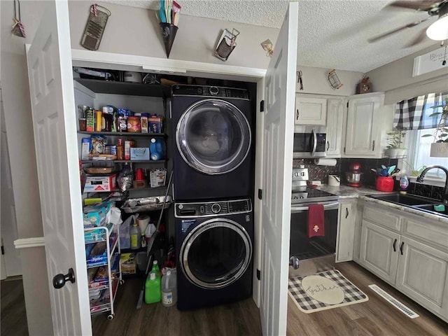 laundry area featuring a textured ceiling, dark hardwood / wood-style flooring, sink, and stacked washer / drying machine