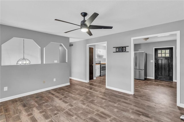 unfurnished living room with dark wood-type flooring and ceiling fan with notable chandelier