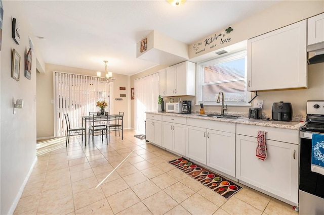 kitchen featuring electric range, sink, light tile patterned floors, an inviting chandelier, and white cabinets