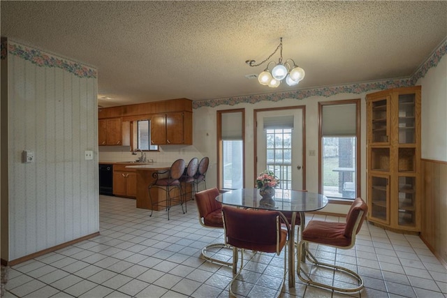 tiled dining space with a textured ceiling, a notable chandelier, wood walls, and sink