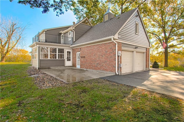 exterior space with a front yard, a garage, a sunroom, a balcony, and a patio