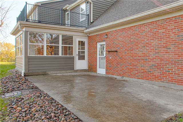 exterior space with a balcony, a patio area, and a sunroom