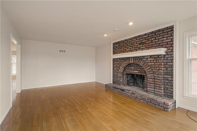 unfurnished living room featuring a brick fireplace and wood-type flooring