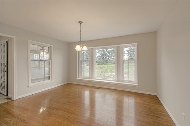 unfurnished dining area with a chandelier and light hardwood / wood-style flooring