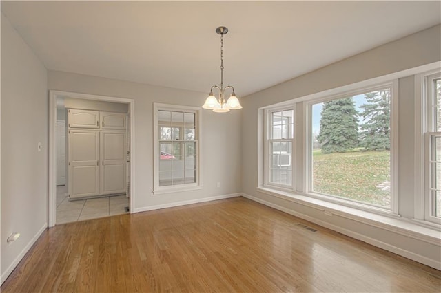 unfurnished dining area with light hardwood / wood-style flooring and a chandelier