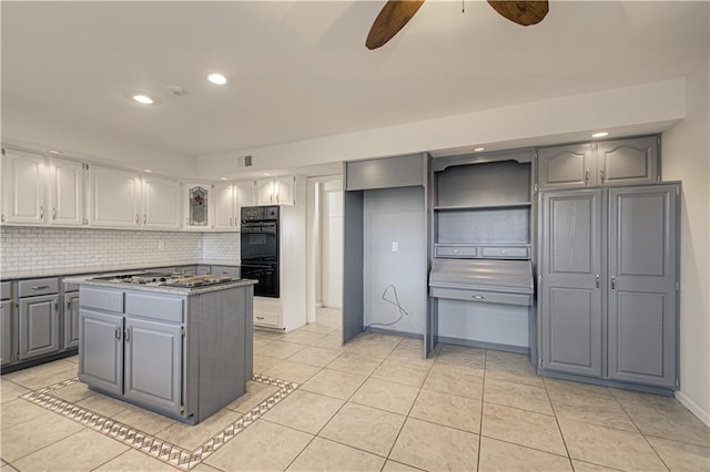 kitchen featuring a kitchen island, black double oven, tasteful backsplash, gray cabinets, and light tile patterned floors