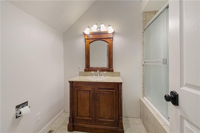 bathroom with tile patterned flooring, vanity, and vaulted ceiling