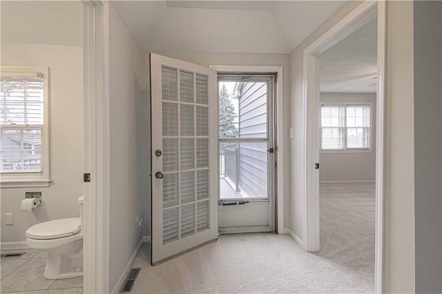 doorway featuring light carpet and vaulted ceiling