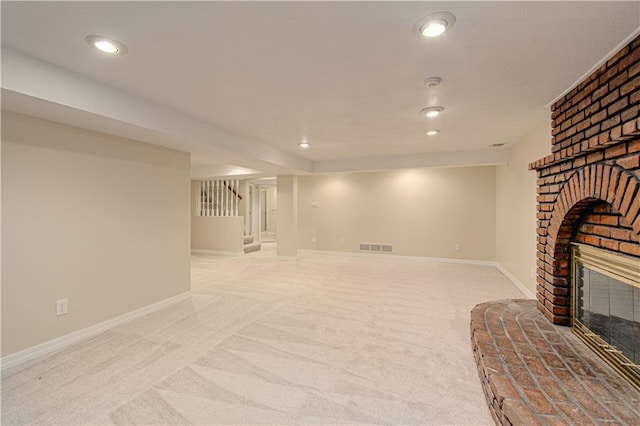 basement featuring light colored carpet and a fireplace