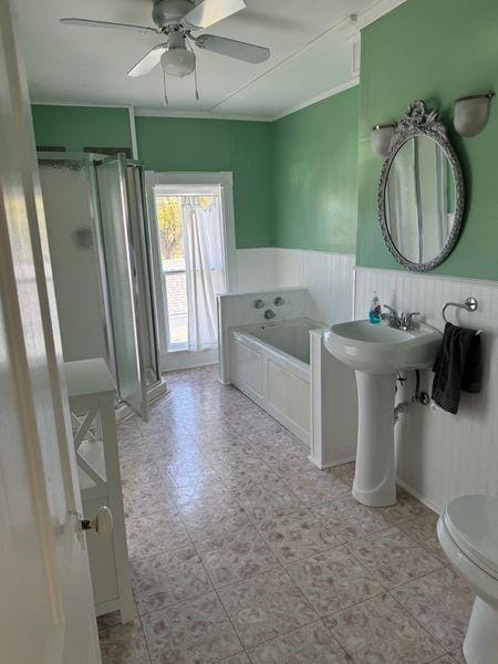 bathroom with crown molding, ceiling fan, toilet, and plus walk in shower