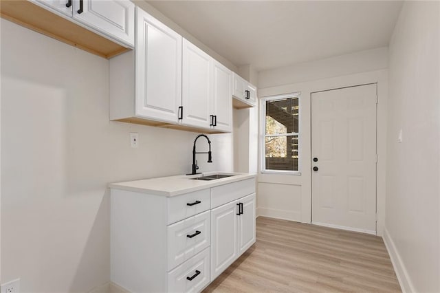 kitchen with white cabinetry, sink, and light hardwood / wood-style floors