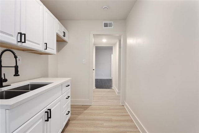 kitchen featuring white cabinets, light hardwood / wood-style flooring, and sink