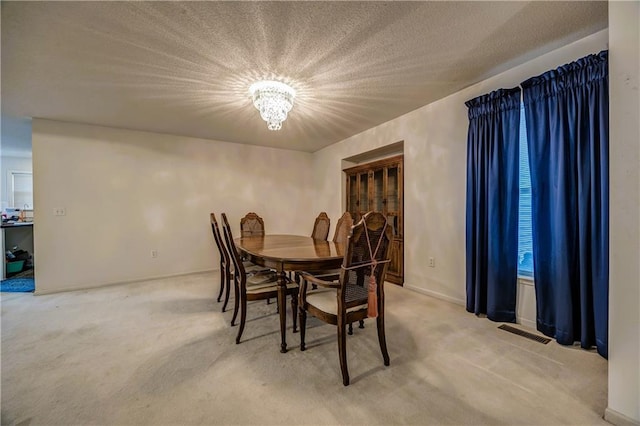 dining area with carpet, a notable chandelier, and a textured ceiling