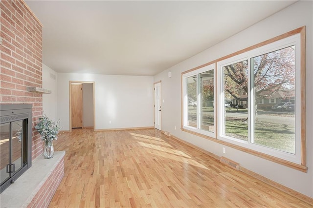 unfurnished living room featuring light wood-type flooring and a fireplace