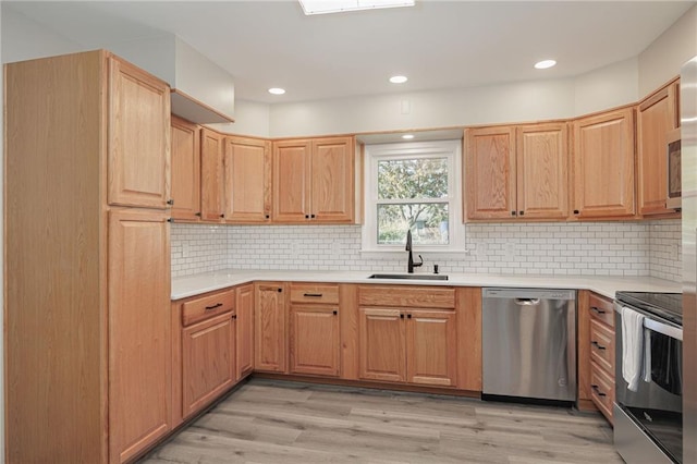 kitchen with light hardwood / wood-style floors, stainless steel appliances, sink, and tasteful backsplash