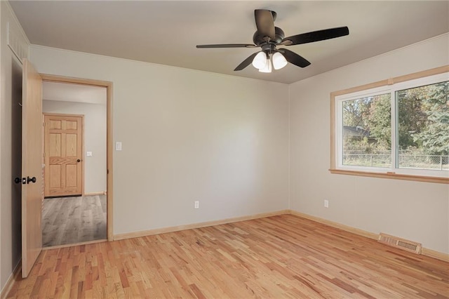 empty room featuring ornamental molding, light wood-type flooring, and ceiling fan