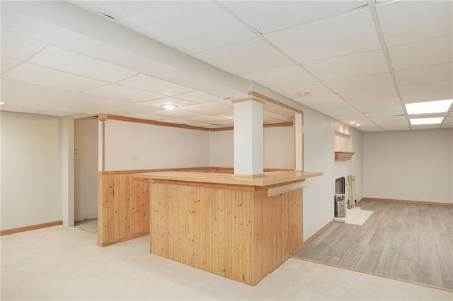 interior space featuring light brown cabinets, light wood-type flooring, butcher block countertops, and a drop ceiling