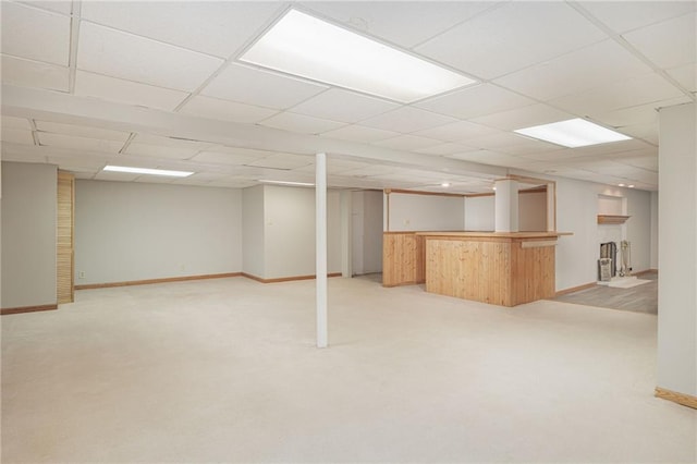 basement featuring bar area, light carpet, and a drop ceiling