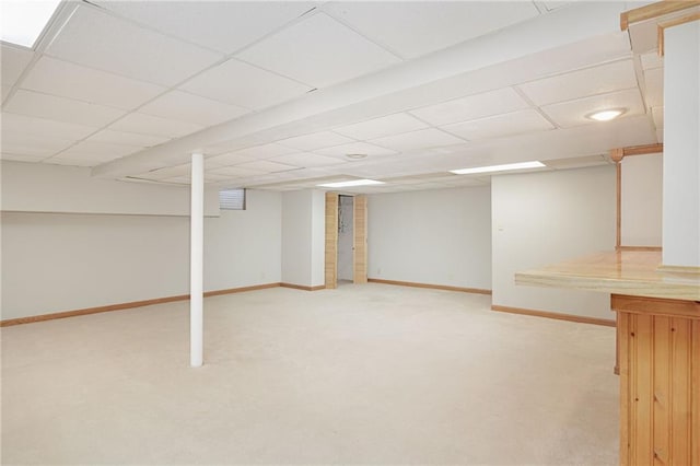 basement featuring light colored carpet and a paneled ceiling