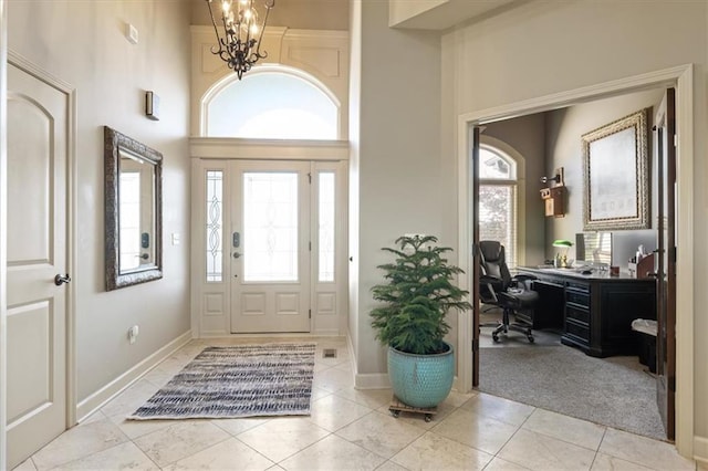 entrance foyer featuring a towering ceiling, a notable chandelier, and light tile patterned floors