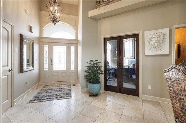 entrance foyer with french doors, a chandelier, a high ceiling, and light tile patterned flooring