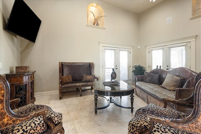 living room featuring a towering ceiling, french doors, and a healthy amount of sunlight