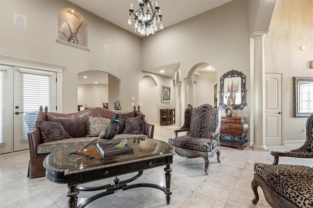 living room featuring high vaulted ceiling, decorative columns, french doors, and a notable chandelier