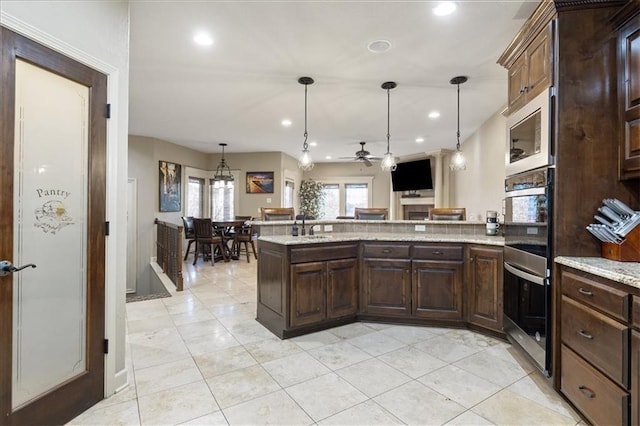 kitchen with hanging light fixtures, stainless steel double oven, ceiling fan, and dark brown cabinetry