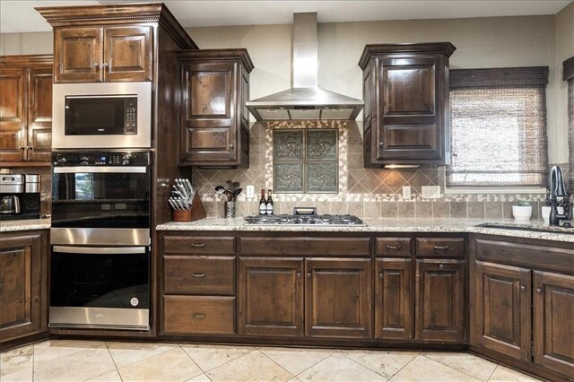 kitchen with tasteful backsplash, appliances with stainless steel finishes, sink, and wall chimney exhaust hood