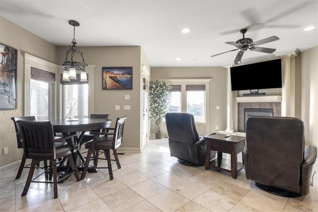 tiled dining area featuring ceiling fan and a tiled fireplace