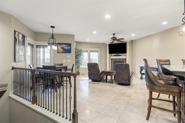 dining area featuring ceiling fan, a tile fireplace, and light tile patterned flooring