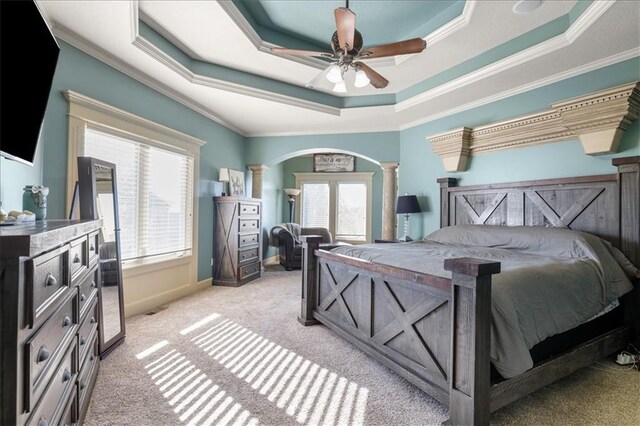 bedroom featuring ceiling fan, light carpet, ornate columns, and a raised ceiling