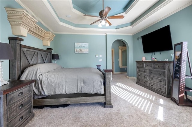 carpeted bedroom with ornamental molding, a tray ceiling, and ceiling fan