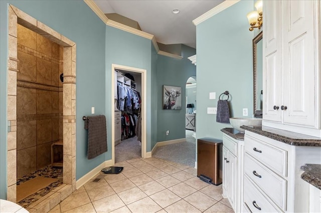 bathroom with vanity, tile patterned floors, tiled shower, and crown molding