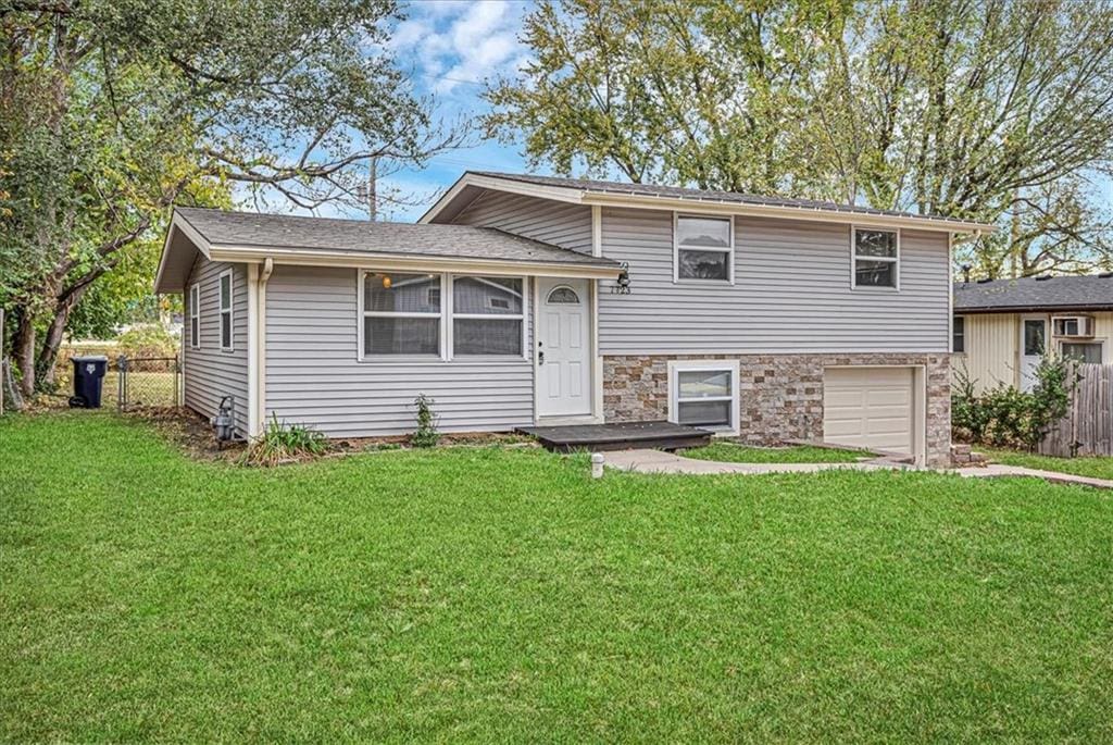 split level home with a garage and a front lawn