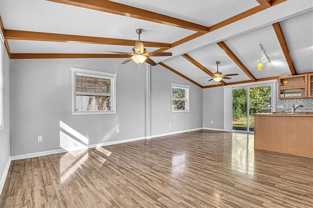 unfurnished living room with vaulted ceiling with beams, hardwood / wood-style flooring, and ceiling fan