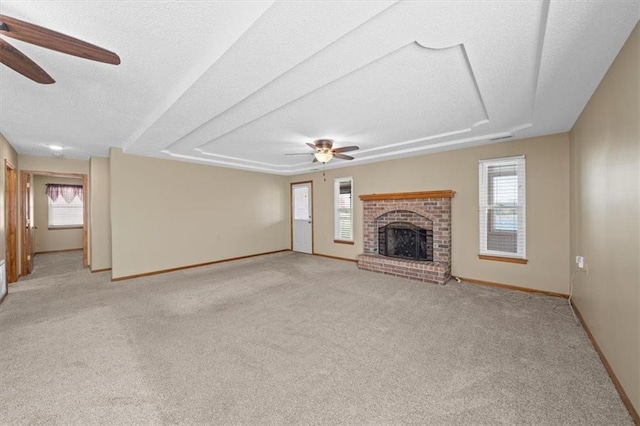 unfurnished living room with a brick fireplace, ceiling fan, a healthy amount of sunlight, and light carpet