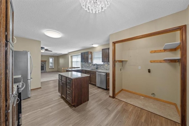 kitchen featuring light hardwood / wood-style floors, a center island, dark brown cabinetry, a textured ceiling, and appliances with stainless steel finishes