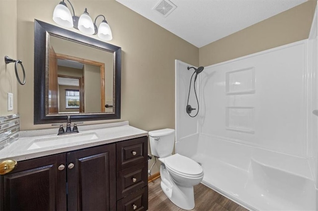 bathroom featuring a shower, hardwood / wood-style flooring, vanity, and toilet