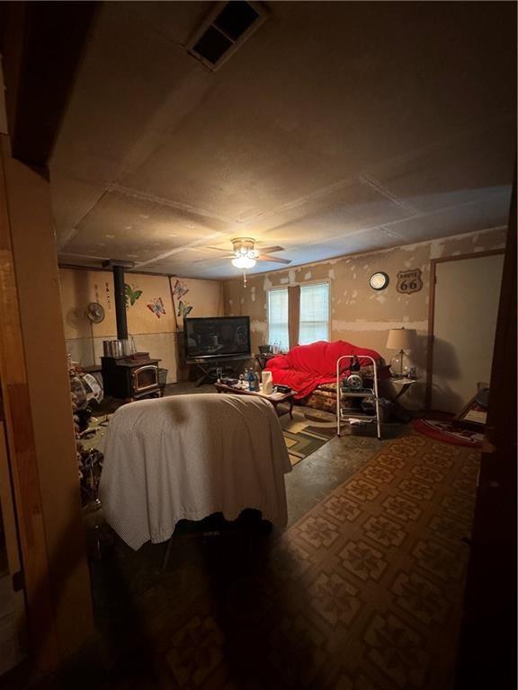 bedroom with ceiling fan and a wood stove