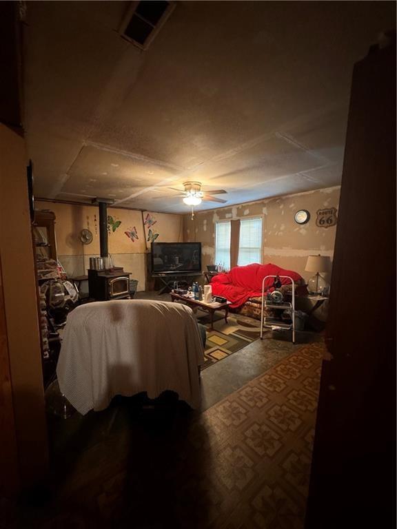 living room featuring a wood stove, carpet flooring, and ceiling fan