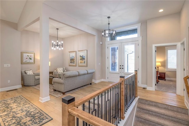 interior space featuring french doors, light wood-type flooring, vaulted ceiling, and an inviting chandelier