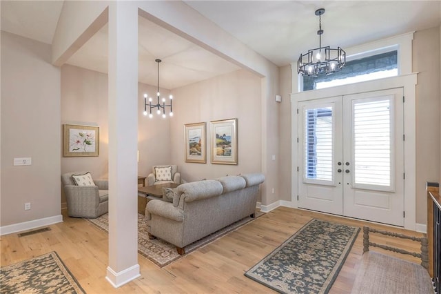 entrance foyer featuring a chandelier, french doors, and light hardwood / wood-style floors