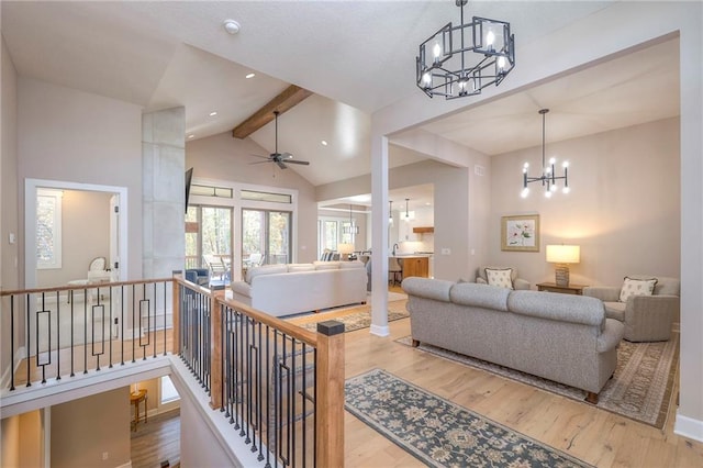 living room with lofted ceiling with beams, ceiling fan with notable chandelier, and wood-type flooring