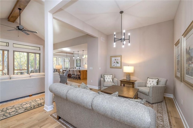 living room with lofted ceiling with beams, ceiling fan with notable chandelier, and light hardwood / wood-style flooring