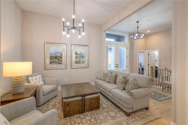 living room featuring light hardwood / wood-style floors, a towering ceiling, and a notable chandelier