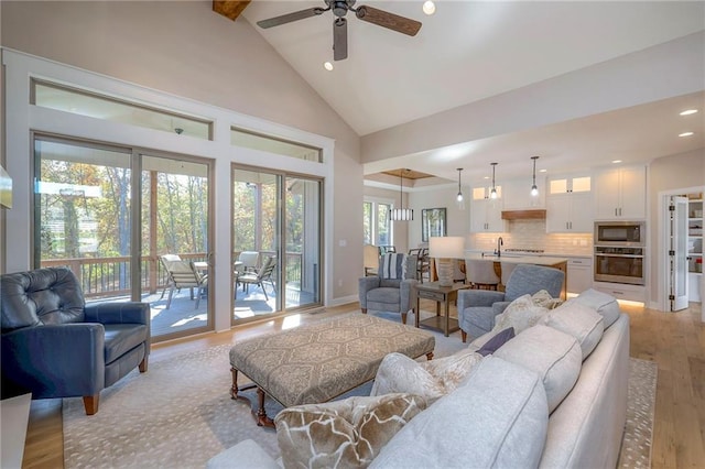 living room featuring high vaulted ceiling, beamed ceiling, ceiling fan, and light hardwood / wood-style flooring