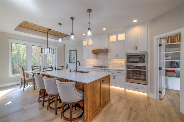 kitchen featuring a kitchen island with sink, white cabinets, sink, and stainless steel appliances