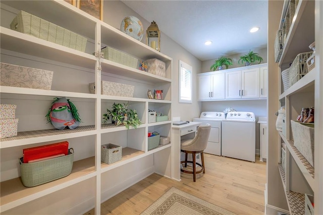 laundry room with light wood-type flooring, cabinets, and washing machine and dryer